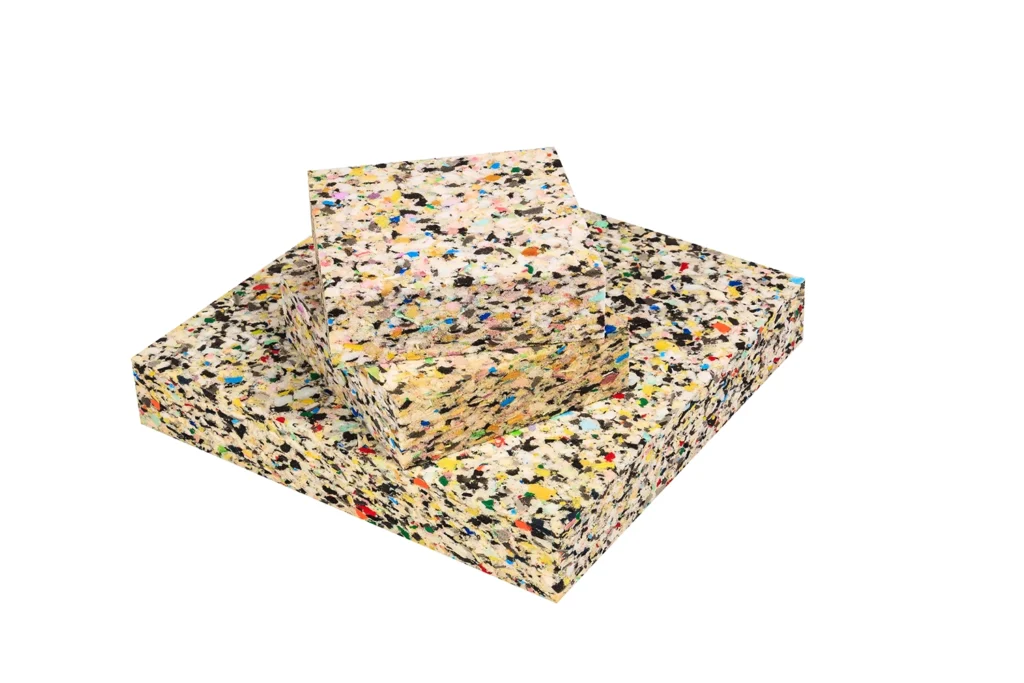 Stacked sheets of high-density rebonded foam made from compressed shredded foam scrap, used in automotive, packaging, and industrial cushioning applications